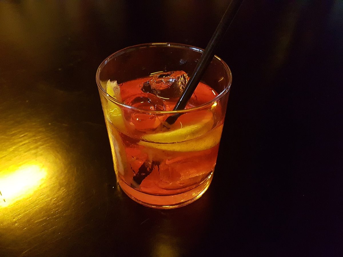 A craft cocktail at one of the best bars in Buenos Aires, lit low over a dark bar