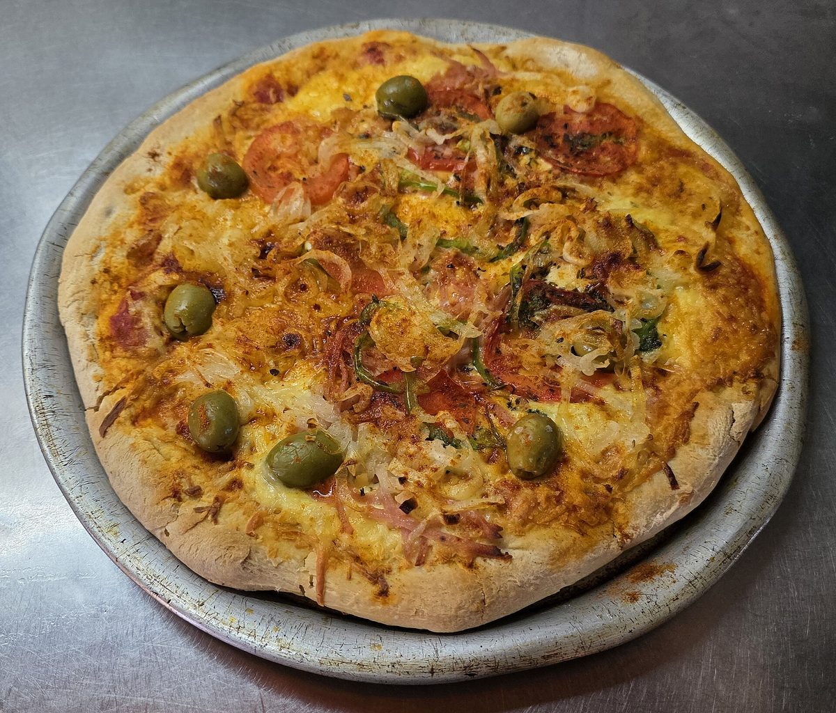 A whole Argentine-style pizza with a thick cheesy crust, tomato, onion and green olives