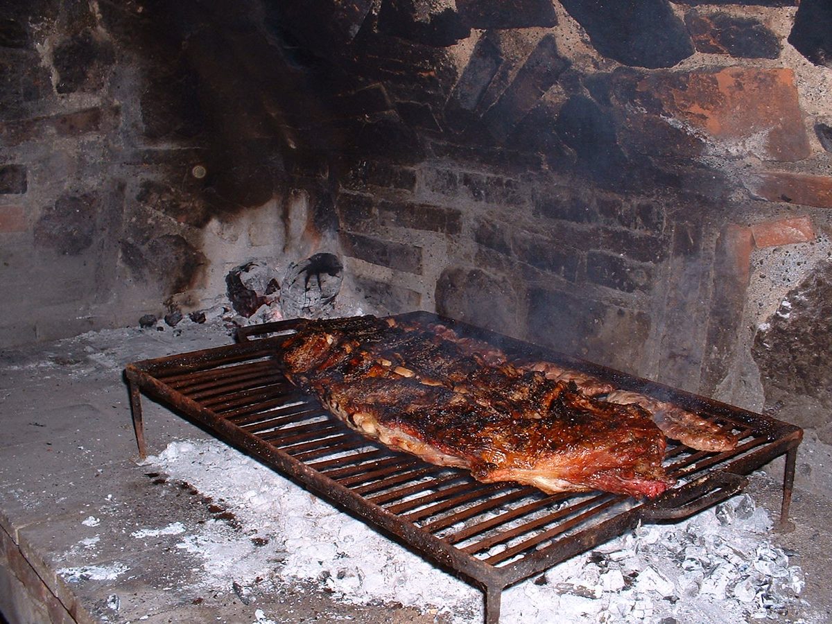 Cuts of beef sizzling on a parrilla grill during a San Telmo food tour