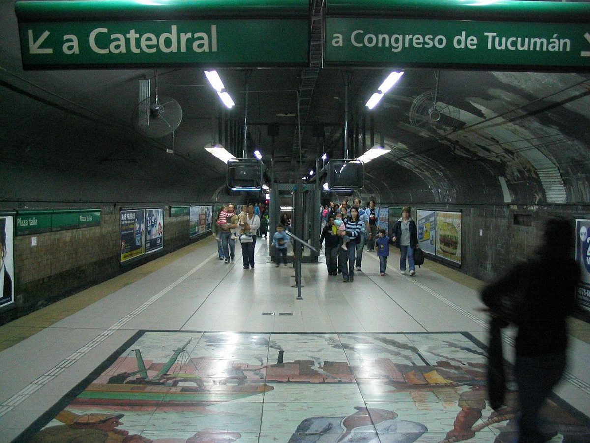 Passengers on a Line D Subte platform at Plaza Italia in Buenos Aires, with signs toward Catedral and Congreso de Tucuman
