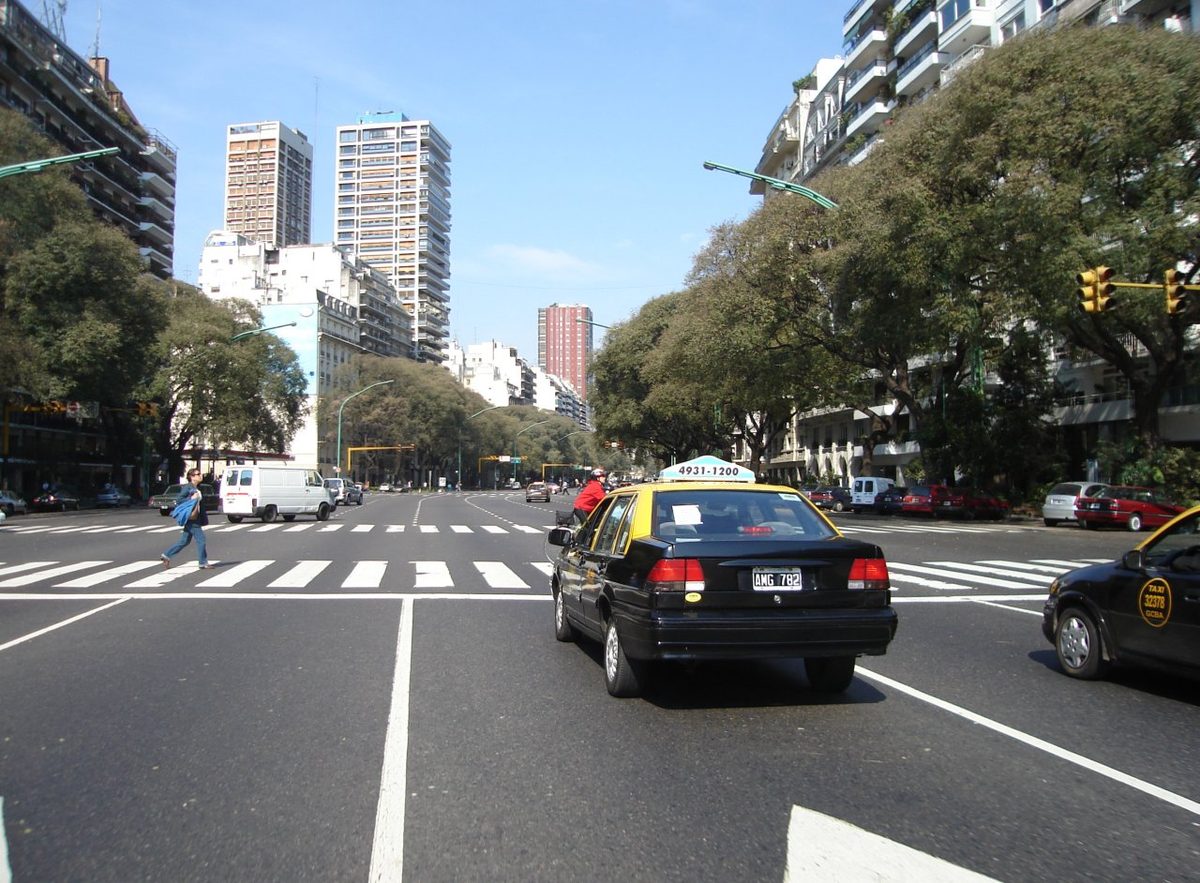 Black-and-yellow Buenos Aires taxi on a wide leafy avenue in the city