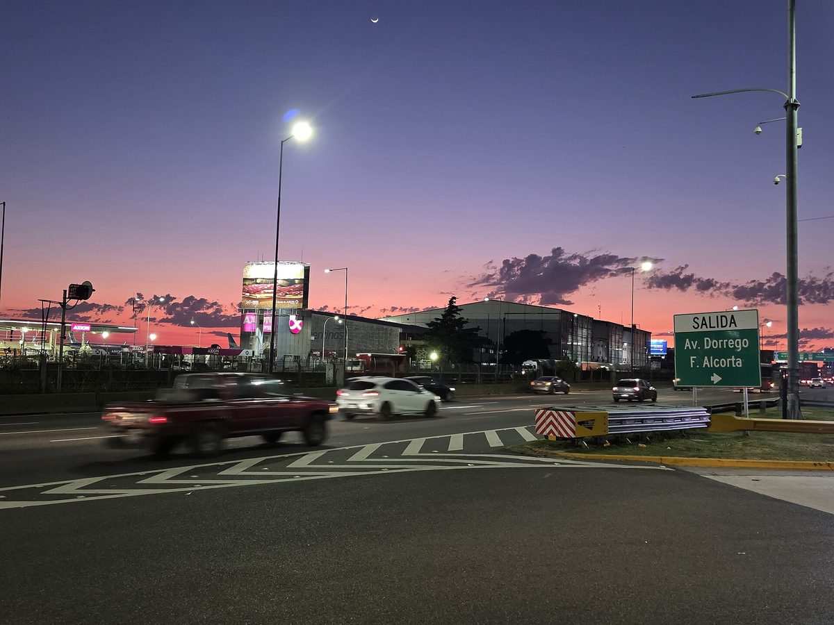 Cars in motion at dusk beside a SALIDA Av. Dorrego highway exit sign near Aeroparque in Buenos Aires