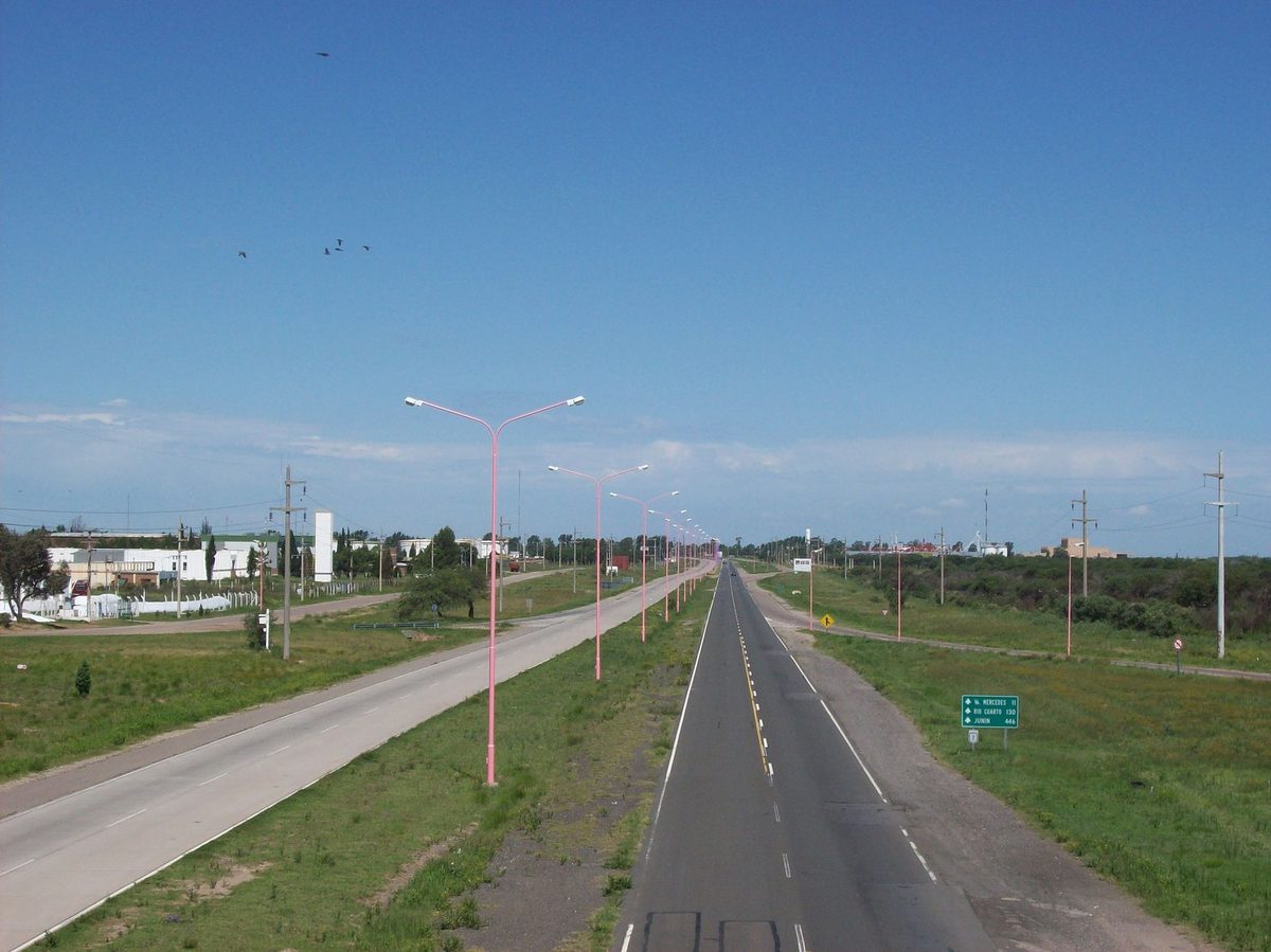 An open divided highway through the Argentine countryside with a road sign for Mercedes, Rio Cuarto and Junin, the kind of ruta a rental car makes easy for a road trip from Buenos Aires