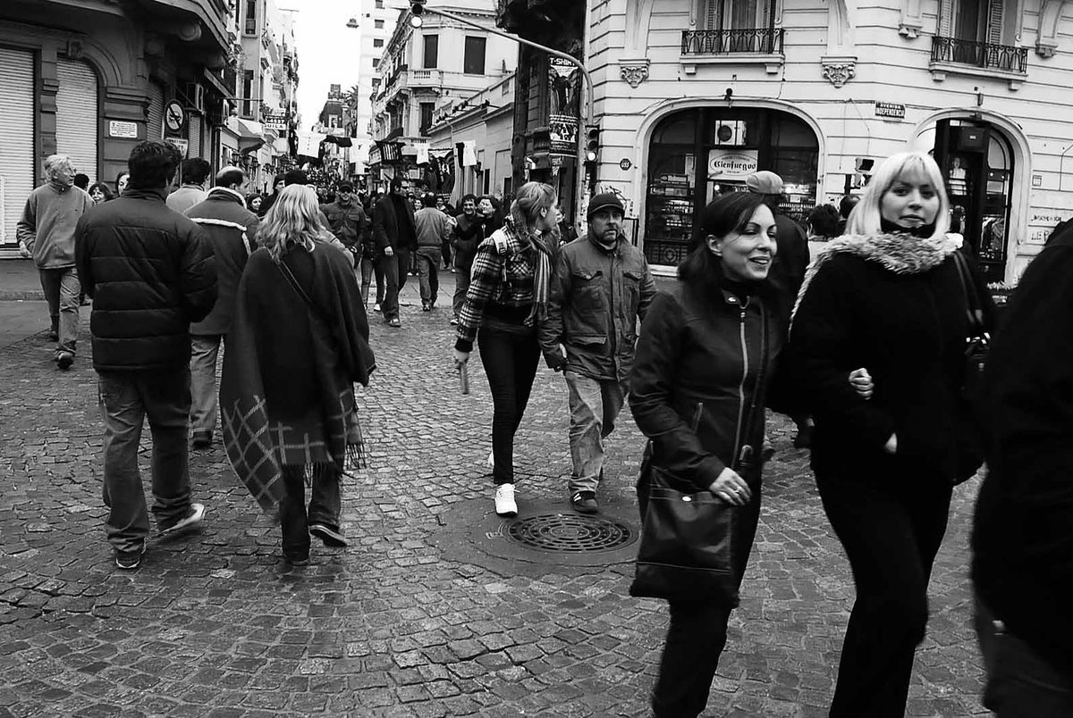 Pedestrians on cobblestone Defensa street lined with colonial buildings in San Telmo, Buenos Aires