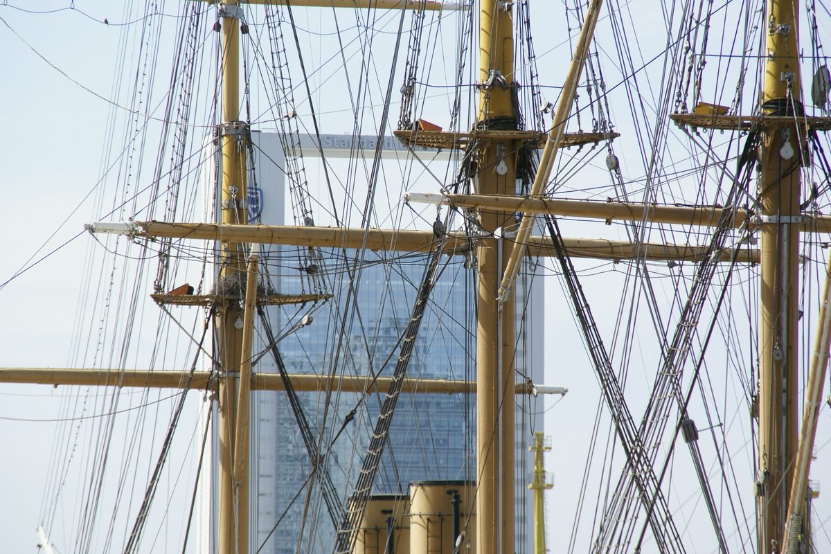 Masts and rigging of the historic Fragata Presidente Sarmiento museum ship against a glass tower in Puerto Madero, Buenos Aires