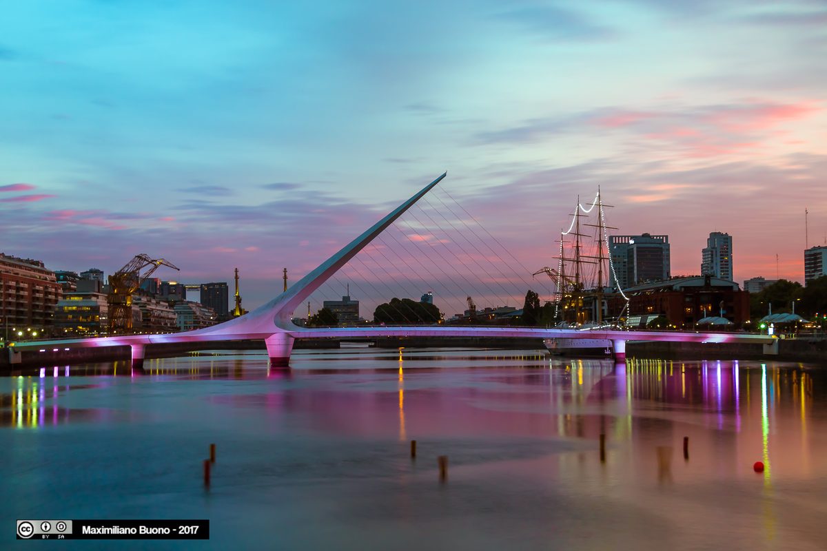 The white rotating Puente de la Mujer footbridge by Santiago Calatrava over a dock at dusk in Puerto Madero, Buenos Aires