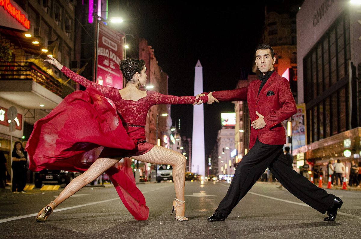 A tango couple dancing on Avenida 9 de Julio in Buenos Aires with the Obelisco behind them