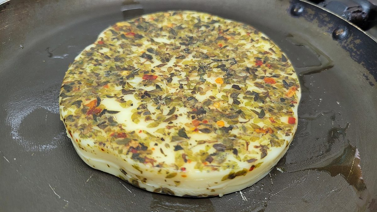 Provoleta, grilled provolone cheese topped with oregano and chili flakes, served before an Argentine asado