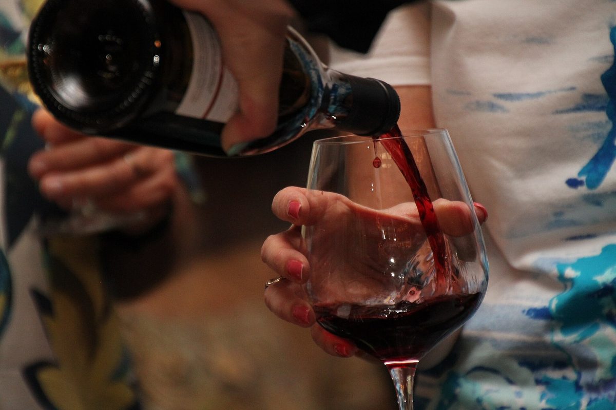 Red wine being poured into a glass during a tasting